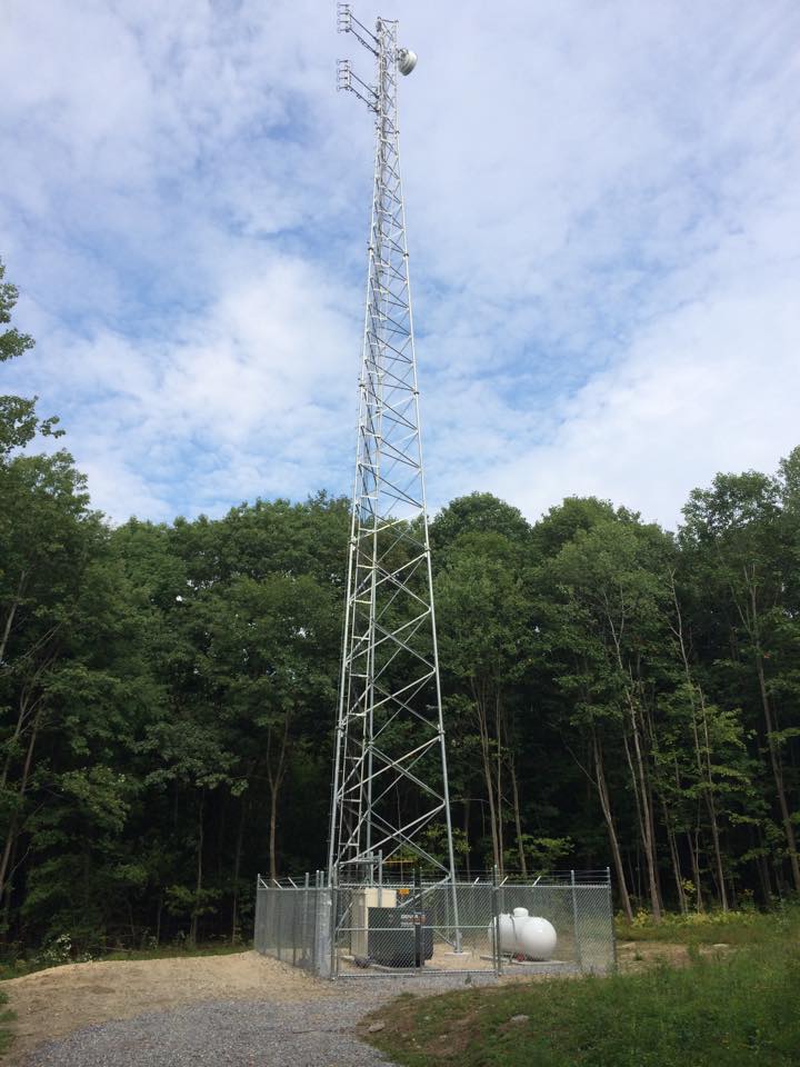 a radio tower in the middle of the woods at day